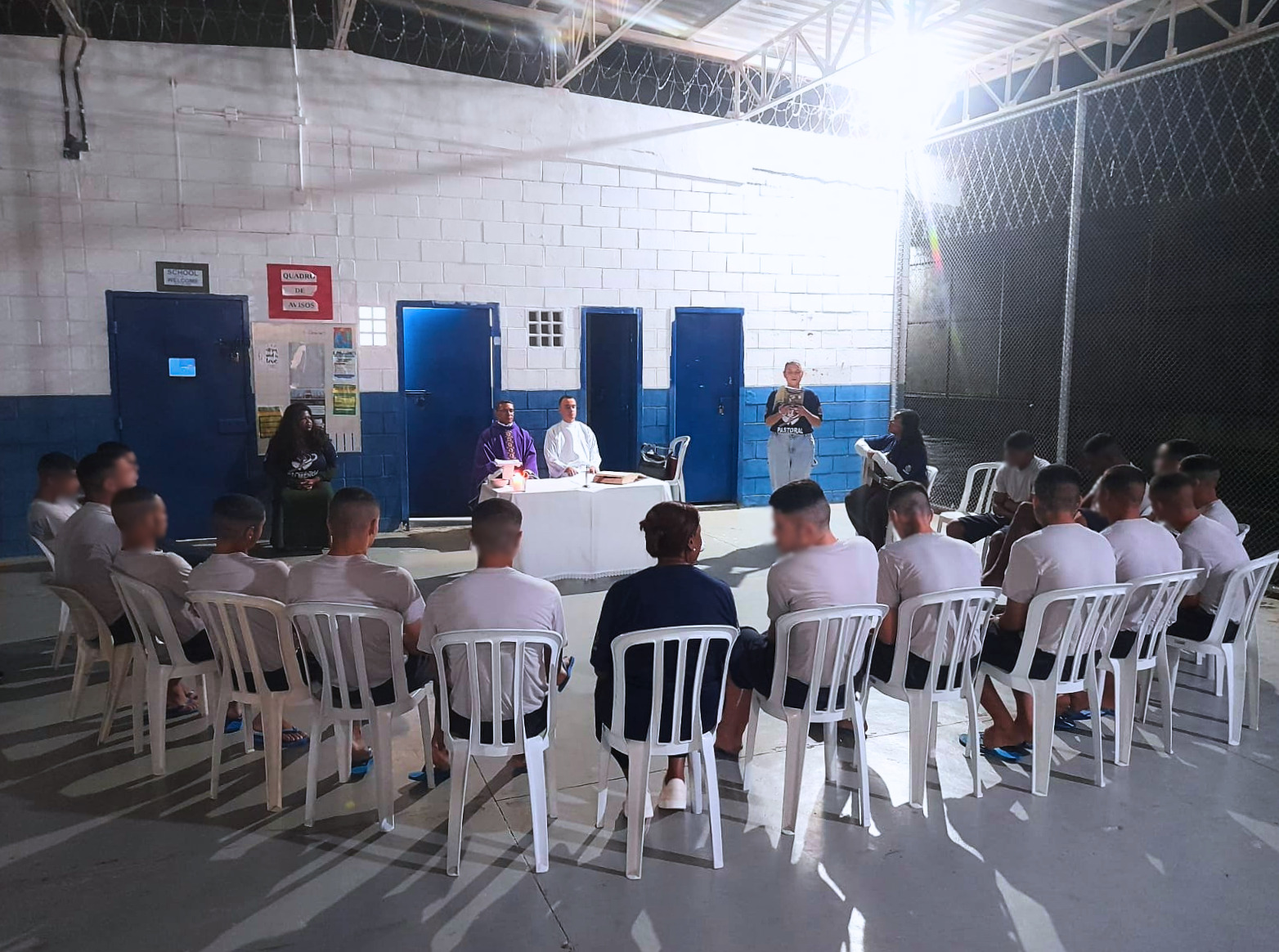 Adolescentes sentados em círculo participam de celebração religiosa em espaço interno do CASA Tamoios, com padre e servidores ao centro, durante a Missa do Lava-Pés.
